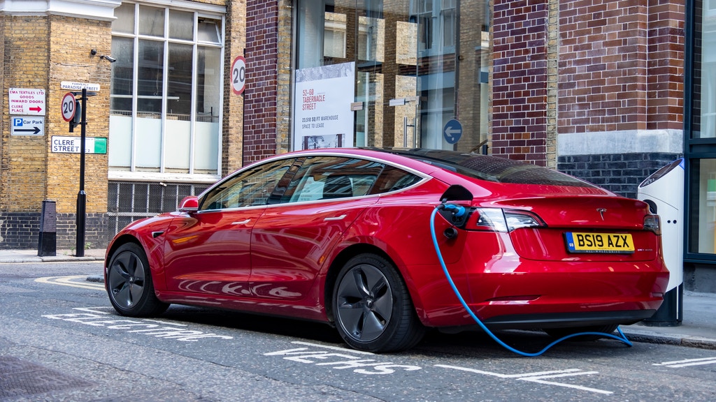 a red tesla parked and charging