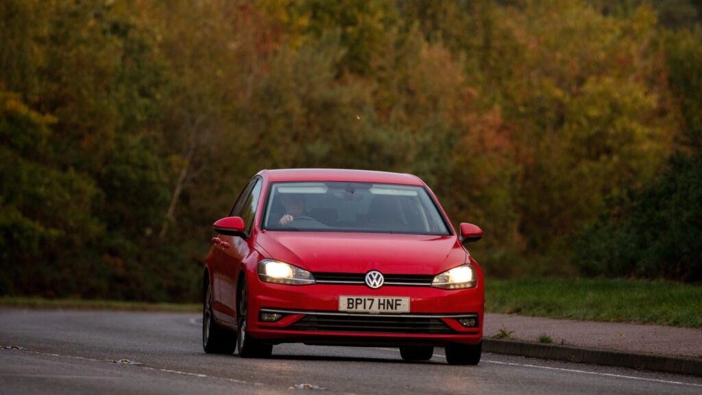 a man driving a red VW polo